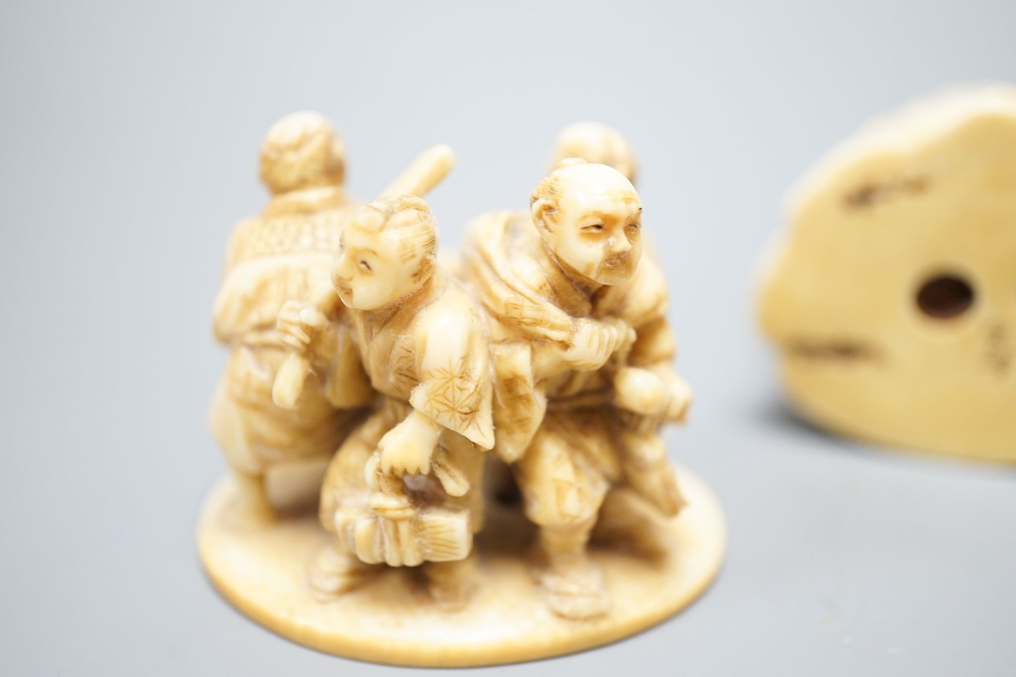 Two Japanese ivory okimono-netsuke of Buddha and attendants and a group of artisans, Meiji period, both signed, tallest 7cm